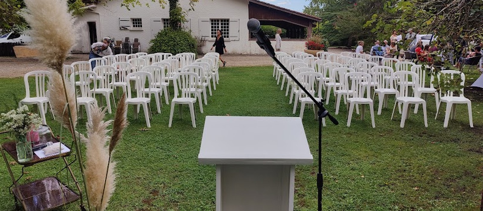 Cérémonie laïque en extérieur, chaises blanches et pupitre prêts pour la cérémonie