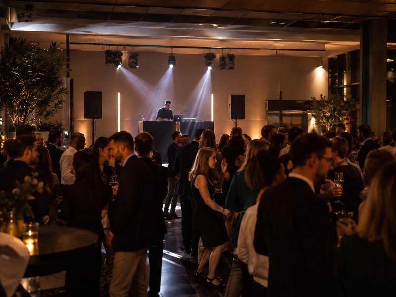 Cocktail d'entreprise en soirée avec DJ sur scène et invités en tenue professionnelle