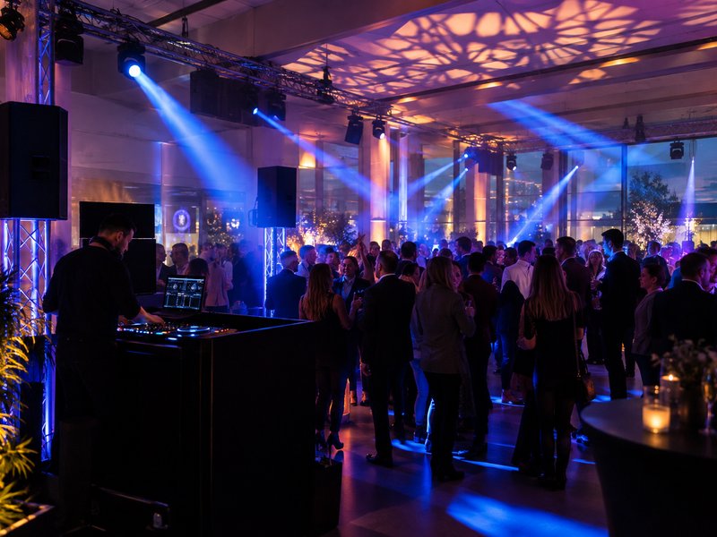Soirée d'entreprise animée avec jeux de lumière bleus et invités sur la piste
