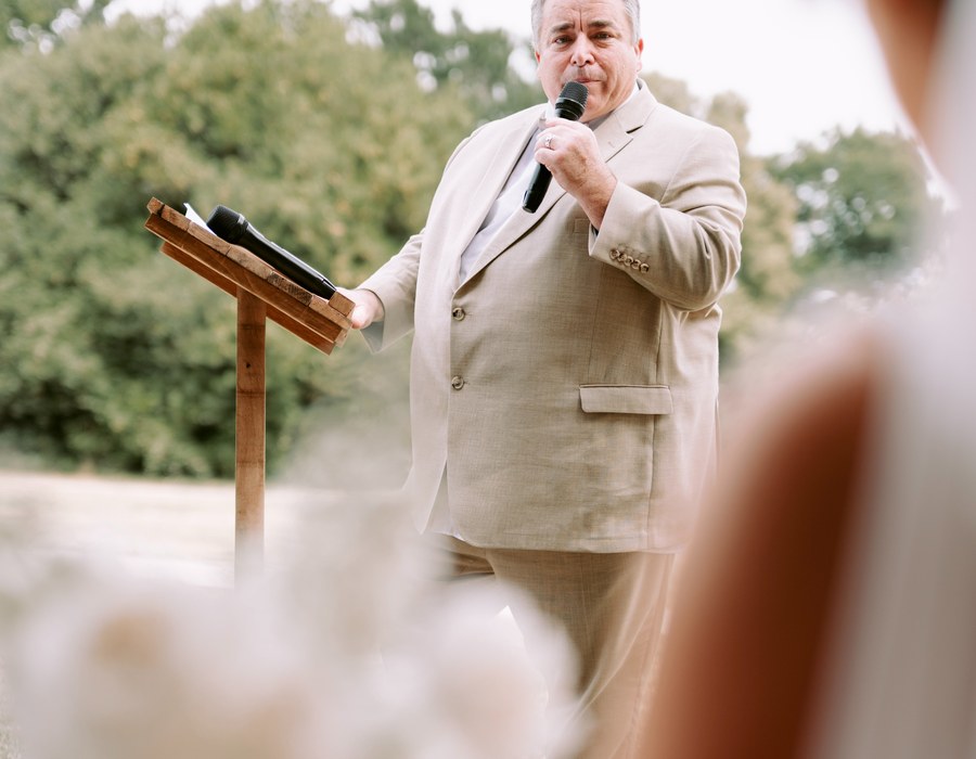Discours d'un proche au micro pendant une cérémonie de mariage en extérieur