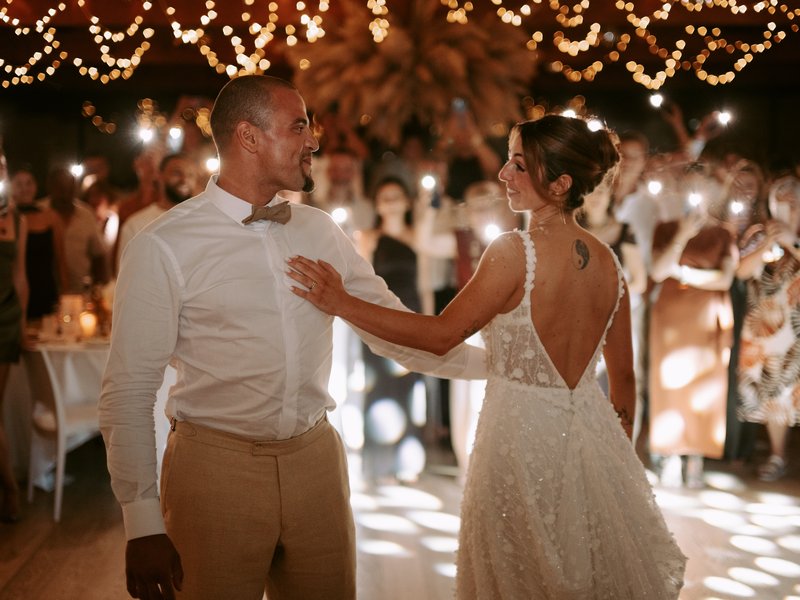 Premier danse des mariés entourés de leurs invités et de guirlandes lumineuses